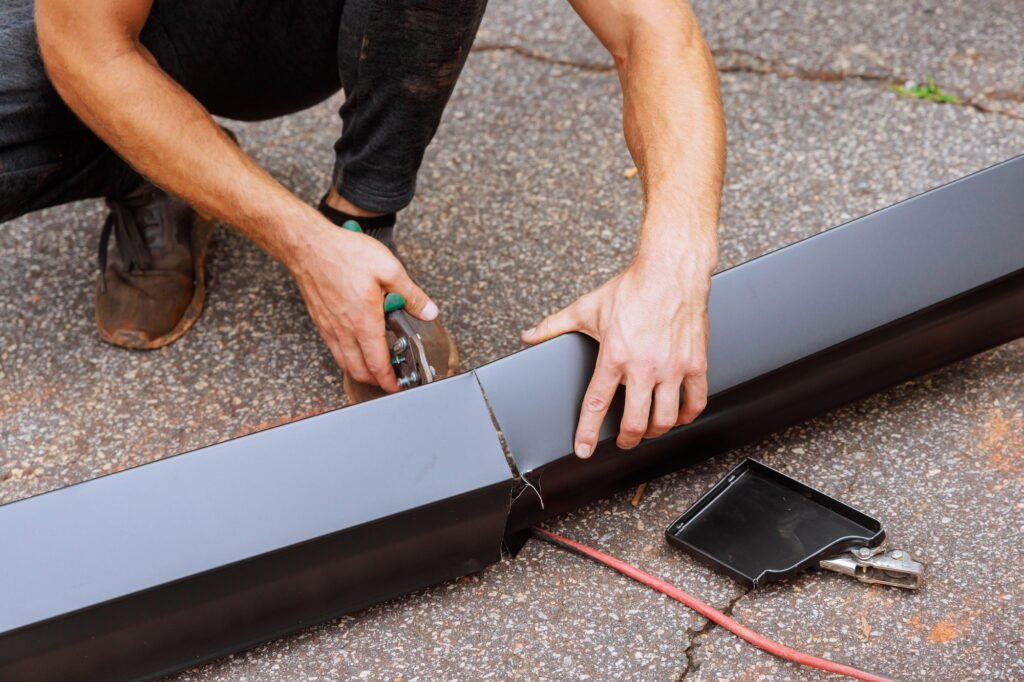 When aluminum rain gutters have been bent on machine tool, a worker cuts them to required size with